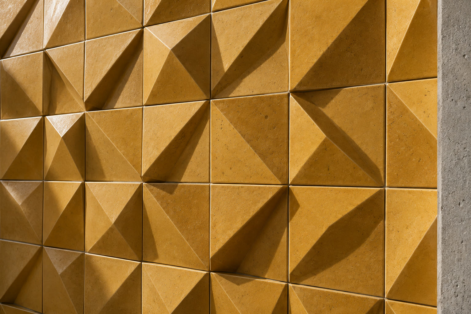Ochre square ceramic tiles with angular folded facets and raking light